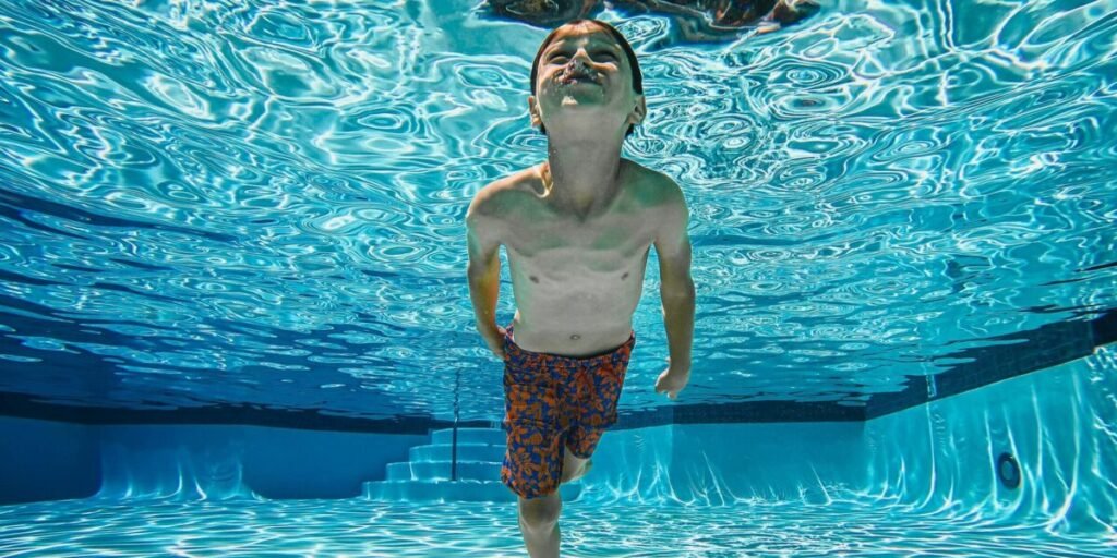 Kid Swimming Underwater in His Home Pool